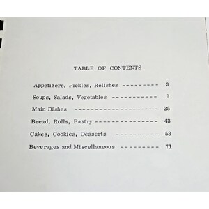 Op de afbeelding: Een witte pagina met zwarte tekst onder de titel TABLE OF CONTENTS. Het bevat de categorie&euml;n: Appetizers, Pickles, Relishes 3; Soups, Salads, Vegetables 9; Main Dishes 25; Bread, Rolls, Pastry 43; Cakes, Cookies, Desserts 53; Beverages and Miscellaneous 71.