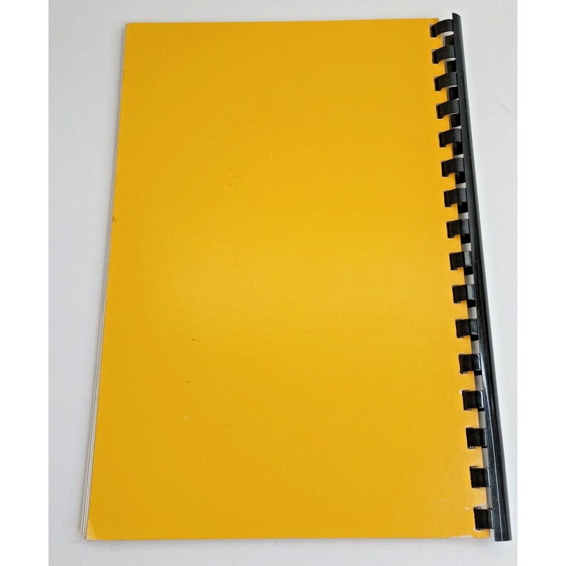 Op de afbeelding: Een rechthoekig notitieboek met een effen felgele kaft en een zwarte plastic spiraalbinding aan de rechterkant. Het notitieboek is verticaal geori&euml;nteerd en heeft een gladde, mat afgewerkte voorkant in een consistente, egale gele kleur.