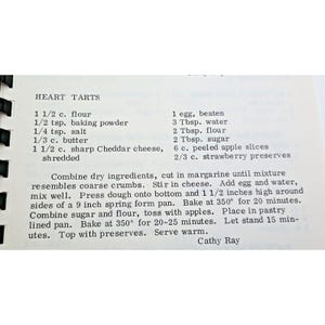 Op de afbeelding: Een gedrukte receptpagina met de titel HEART TARTS met zwarte tekst op een witte achtergrond. Het bevat ingredi&euml;nten zoals bloem, bakpoeder, zout, boter, Cheddar-kaas, ei, water, suiker, appelschijfjes en aardbeienjam, plus de instructies.