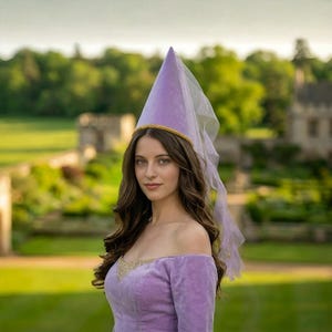 A woman wearing a purple dress and a purple hat stands in a garden, with a castle visible in the background.