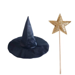 A black witch's hat and a gold glitter star on a stick are shown against a white background.
