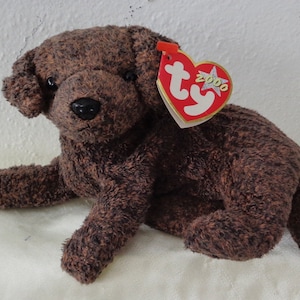 May include: Brown plush dog toy with a Ty Beanie Baby tag that says "2000".
