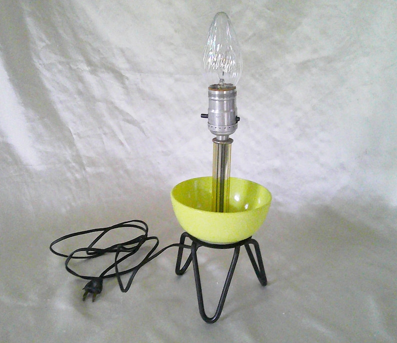 May include: A yellow ceramic bowl lamp with a black metal tripod base and a clear glass bulb.
