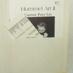 May include: A book titled "Hummel Art II Current Price List" with a picture of a Hummel figurine on the cover. The book is open to a page with a list of Hummel figurines and their prices.
