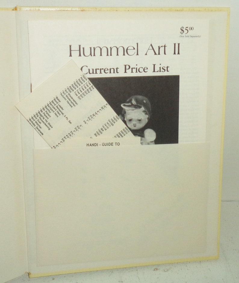May include: A book titled "Hummel Art II Current Price List" with a picture of a Hummel figurine on the cover. The book is open to a page with a list of Hummel figurines and their prices.