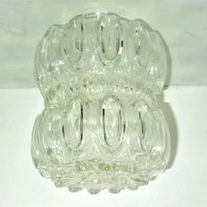 May include: A clear glass light fixture shade featuring a double-tiered design with repeating vertical oval indentations. The glass has a textured, pressed pattern throughout, creating a series of rounded, bulbous sections stacked vertically.