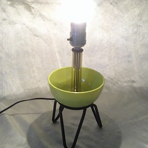 May include: A green ceramic bowl lamp with a black metal base and a clear light bulb.