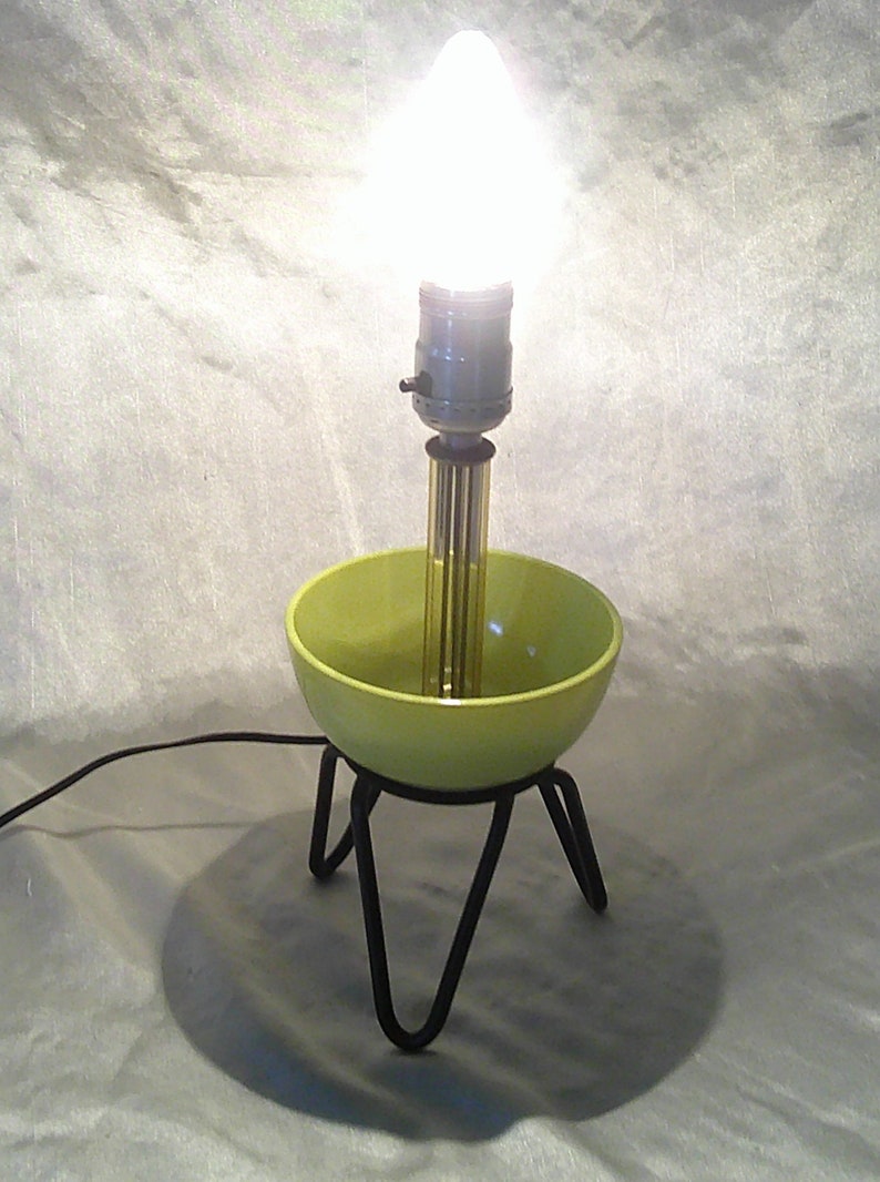 May include: A green ceramic bowl lamp with a black metal base and a clear light bulb.