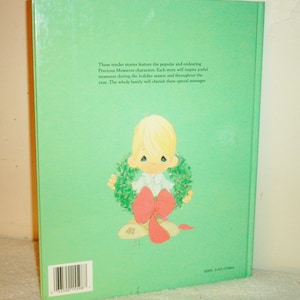 May include: The back cover of a book featuring a Precious Moments character holding a Christmas wreath. The text on the back cover reads: "These tender stories feature the popular and endearing Precious Moments characters. Each story will inspire joyful moments during the holiday season and throughout the year. The whole family will cherish these special messages."