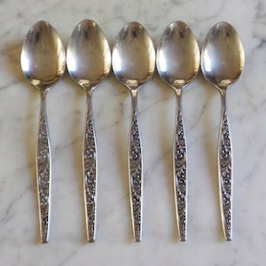 Puede incluir: Cinco cucharas de plata con un diseño floral adornado en el mango.