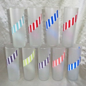 May include: Set of ten frosted glass tumblers with colorful striped designs. Each glass features a different color combination of red, blue, white, green, and purple stripes.