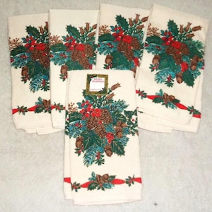 May include: Set of six off-white holiday towels. Each towel features a festive design of pinecones, holly, and red berries. A red ribbon with green accents adorns the bottom. The towels are perfect for seasonal decor.