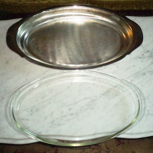 May include: A silver oval serving tray with a glass lid. The tray has a decorative rim and the lid is clear.