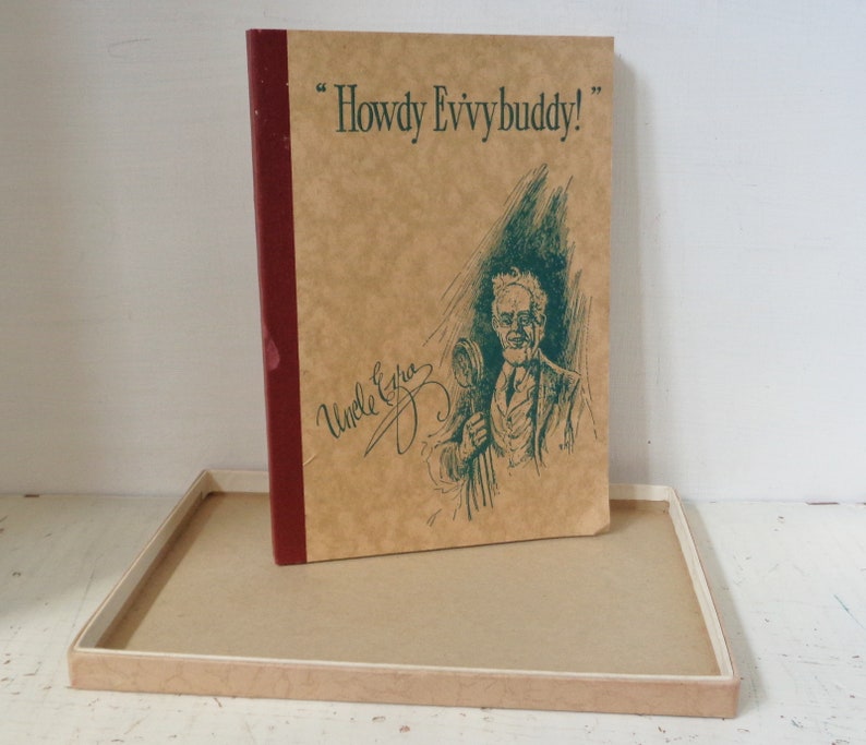 May include: A brown book with a red spine and the text "Howdy Evvybuddy!" on the front cover. The book has a green illustration of a man with a mustache and a cane. The text "Uncle Ezra" is written in cursive on the front cover.
