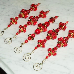 May include: Five red and gold beaded ornaments with a gold wire loop at the top. The beads are arranged in a diamond shape.