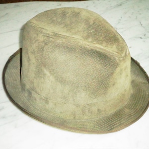 May include: A green felt fedora hat with a wide brim. The hat has a slightly worn look and is made of a soft material.