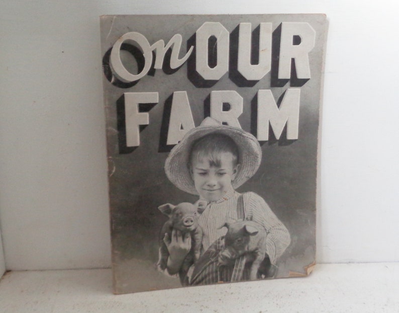 Peut inclure: Photographie en noir et blanc d'un jeune gar&ccedil;on portant un chapeau de paille et tenant deux porcelets. La photo est sur une couverture de livre avec le titre "On Our Farm" en grandes lettres audacieuses.