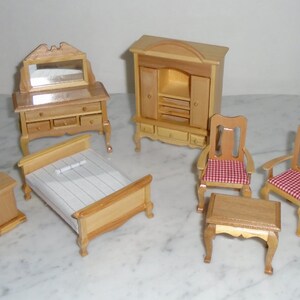 May include: A miniature dollhouse furniture set with a wooden bed, dresser with a mirror, armoire, two chairs, and a table. The chairs have red and white checkered cushions.