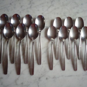 May include: A set of 14 silver spoons with a modern design. The spoons are arranged in two rows, with the handles pointing towards the center.