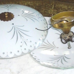 以下が含まれることがあります： 繊細なエッチングされた花のデザインが施された、白いガラス製の天井照明器具が2つ。器具は分離されており、真鍮製の取り付け金具が示されています。
