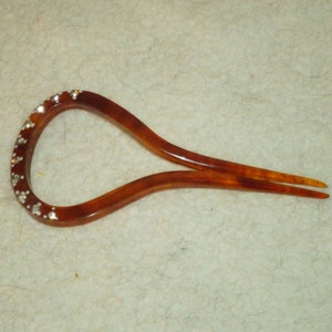 May include: A brown tortoiseshell hair comb with a row of clear rhinestones along the top edge.