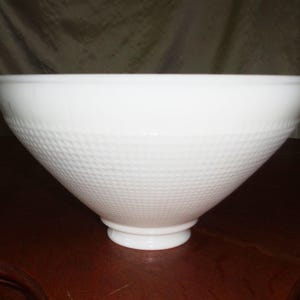 May include: A white, cone-shaped bowl with a textured, diamond-patterned exterior. The bowl has a wide rim and a small, circular base. The bowl is made of a solid, opaque material.