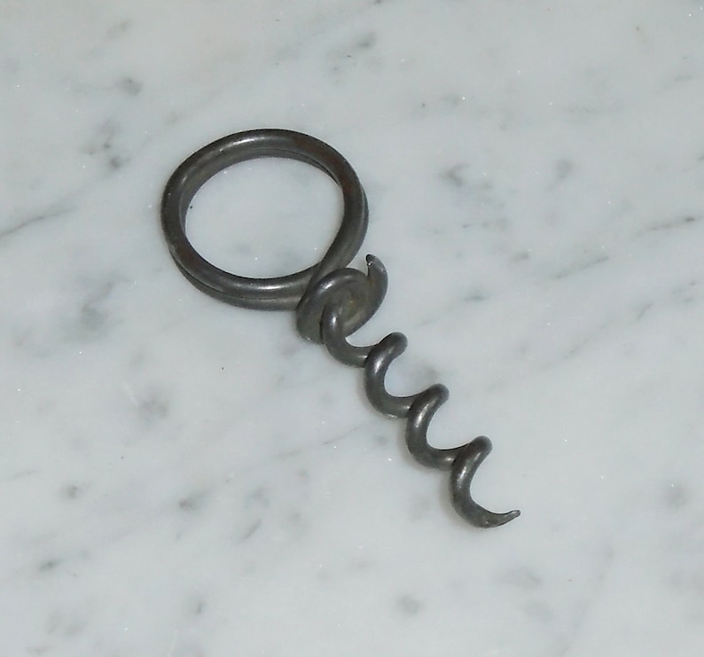 May include: A silver metal corkscrew with a ring handle.