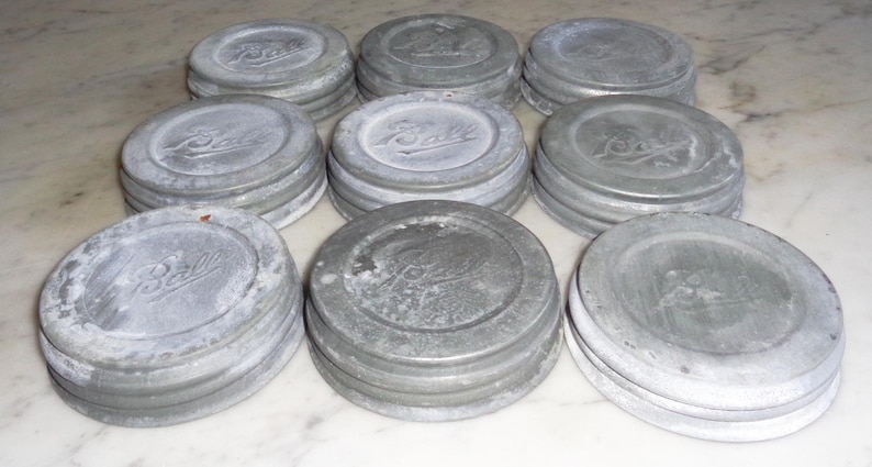 May include: Ten vintage silver-colored metal jar lids with the word "Ball" embossed on each lid.