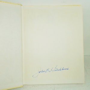 May include: A white book with a blue ink signature that reads "John R. Falkenberg".