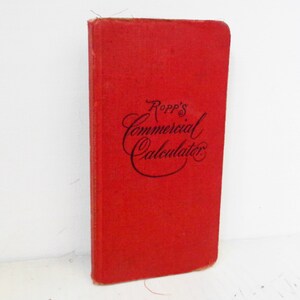 Puede incluir: Un libro rojo de tapa dura titulado "Ropp's Commercial Calculator".