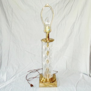 May include: A gold table lamp with a clear crystal base and a gold shade. The base is decorated with a diamond pattern.
