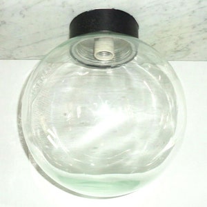 May include: A clear glass globe light fixture with a black metal base and a white electrical socket.