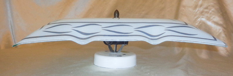 May include: White ceiling light fixture with a white and gray patterned glass shade. The shade has a decorative design of wavy lines.