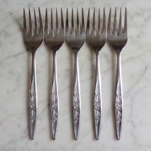May include: Six silver forks with floral designs on the handles.