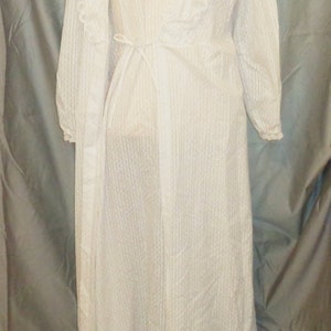 Puede incluir: Camis&oacute;n blanco de encaje con una bata a juego. El camis&oacute;n tiene un escote en V y un lazo en la cintura. La bata tiene mangas largas y un ribete de encaje.