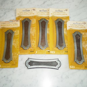 May include: Six packages of cabinet backplates, each with a silver backplate and a brown backing. The packages are yellow with black text that reads "Quality Cabinet Accessories" and "Backplate". The backplates are labeled "National Lock" and "W5330-2A".