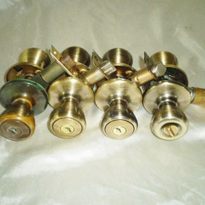 Puede incluir: Cinco pomos de puerta de latón con agujeros para llaves. Los pomos están en diferentes estados de desgaste, algunos muestran signos de edad y uso.