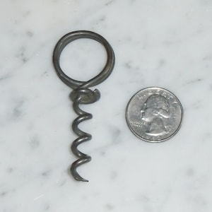 May include: A silver metal corkscrew with a loop handle. The corkscrew is about the size of a US quarter.