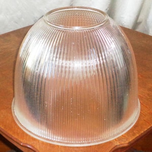 Puede incluir: Una pantalla de lámpara de vidrio transparente con textura acanalada. La pantalla tiene forma de cúpula y un borde liso y redondeado.