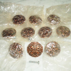 May include: Ten copper cabinet knobs with a decorative floral design. The knobs are packaged in individual plastic bags. One screw is included.