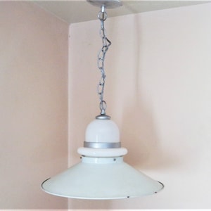 May include: A white pendant light fixture with a silver chain and a white metal shade. The shade has a layered design with a smaller, round top and a larger, flat bottom.