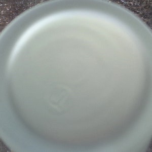 May include: A close-up of a frosted glass bottle cap with a small, circular indentation.