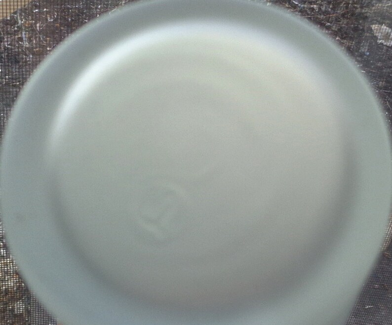 May include: A close-up of a frosted glass bottle cap with a small, circular indentation.