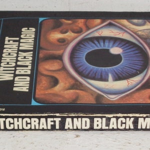 May include: A black book with a colourful illustration of an eye on the cover. The title of the book is "Witchcraft and Black Magic" by Peter Haining. The book is part of the "Knowledge Through Colour" series.