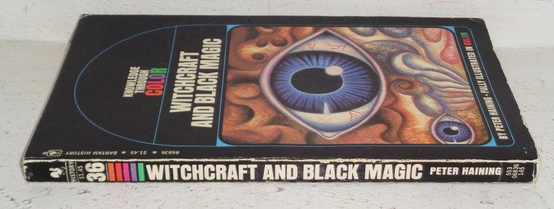 May include: A black book with a colourful illustration of an eye on the cover. The title of the book is "Witchcraft and Black Magic" by Peter Haining. The book is part of the "Knowledge Through Colour" series.