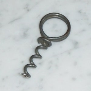 May include: A silver metal corkscrew with a coiled screw and a ring handle.