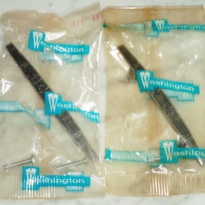 Puede incluir: Dos bolsas de plástico transparentes que contienen dos emblemas de coche de metal plateado con la palabra "Washington" impresa en azul en cada emblema. Cada bolsa contiene dos tornillos.