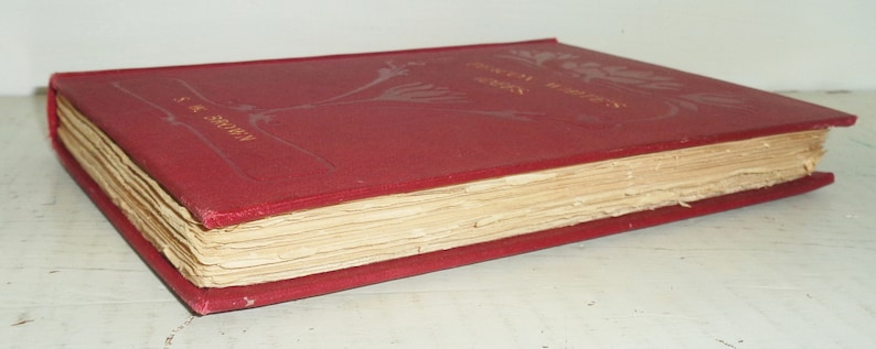 May include: A vintage, red hardcover book with gold lettering and floral designs. The book's pages are aged, and the cover shows signs of wear. The author's name, S.K. Brown, is visible on the spine. The book is lying on a white surface.