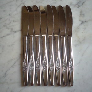 May include: Set of ten silver dinner knives with a rose design on the handle.