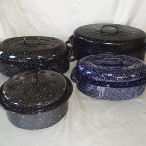 May include: Four oval-shaped enamel baking dishes with lids. The dishes are black and blue with white speckles. The lids have small holes for steam release.
